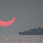 The sun, partially blocked by the moon, rises above the sea in Al Wakrah, Qatar, Dec. 26, 2019. Facebook and Twitter users were quick to draw comparisons between the reddened partial eclipse to "devil horns."