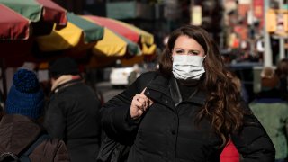 A woman, who declined to give her name, wears a mask, Thursday, Jan. 30, 2020 in New York. She works for a pharmaceutical company and said she wears the mask out of concern for the coronavirus. "I'd wear a mask if I were you," she said. For the first time in the U.S., the new virus from China has spread from one person to another, health officials said Thursday. (AP Photo/Mark Lennihan)
