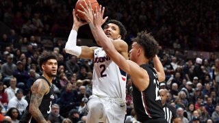 Connecticut's James Bouknight (2) shoots over Cincinnati's Zach Harvey, right, as Cincinnati's Jarron Cumberland, left, looks on in the second half of an NCAA college basketball game, Sunday, Feb. 9, 2020, in Storrs, Connecticut.