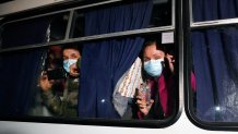 Ukrainian passengers evacuated from the Chinese city of Wuhan, look though a bus window outside Novi Sarzhany, Ukraine, Thursday, Feb. 20, 2020. Several hundred residents in Ukraine's Poltava region protested to stop officials from quarantining the evacuees in their village because they feared becoming infected. Demonstrators put up road blocks and burned tires, while Ukrainian media reported that there were clashes with police, and more than 10 people were detained. (AP Photo/Efrem Lukatsky)