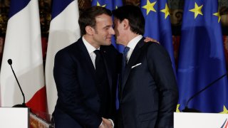 Emmanuel Macron, left, puts his arm around the shoulder of Italian Premier Giuseppe Conte and gives him a kiss on both cheeks.