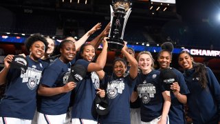 Connecticut players hold up the American Athletic Conference championship trophy the end of an NCAA college basketball game against Cincinnati in the American Athletic Conference tournament finals at Mohegan Sun Arena, Monday, March 9, 2020, in Uncasville, Connecticut.