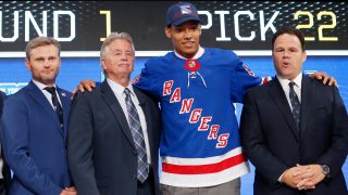 File photo of K'Andre Miller, second from right, wears a New York Rangers jersey and cap after being selected by the team during the NHL hockey draft in Dallas.