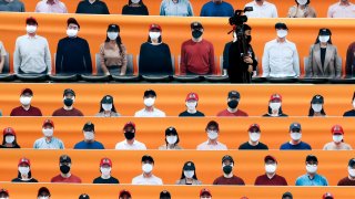 A TV cameraman walks through the spectators' seating which are covered with pictures of fans, before the start of a regular season baseball game between Hanwha Eagles and SK Wyverns in Incheon, South Korea, Tuesday, May 5, 2020. South Korea's professional baseball league start its new season on May 5, initially without fans, following a postponement over the coronavirus.