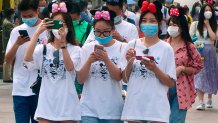 Visitors, wearing face masks, enter the Disneyland theme park in Shanghai as it reopened, Monday, May 11, 2020. Visits will be limited initially and must be booked in advance, and the company said it will increase cleaning and require social distancing in lines for the various attractions.