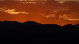 Clouds are illuminated from below as the sun sets behind the Rocky Mountains while residents remain indoors despite the lifting of many restrictions to stop the rise of the new coronavirus late Tuesday, May 19, 2020, in Denver.