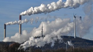 This Jan. 16, 2020 file photo shows a Uniper energy company coal-fired power plant and a BP refinery beside a wind generator in Gelsenkirchen, Germany.