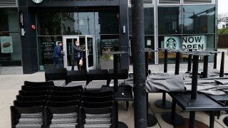 FILE - In this May 21, 2020 file photo, patrons to a Starbucks in the Chicago neighborhood of Hyde Park walk past stacked chairs and tables.