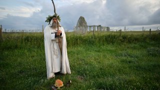 An Archdruid performs a ritual near to the cordoned off Stonehenge as a small group of people gathered to celebrate the Summer Solstice, the longest day of the year, near Salisbury, England, Sunday, June 21, 2020.