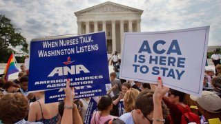 In this June 25, 2015, file photo, supporters of the Affordable Care Act hold up signs as the opinion for health care is reported outside of the Supreme Court in Washington, DC.