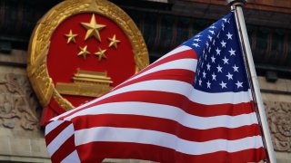 In this Nov. 9, 2017 file photo, an American flag is flown next to the Chinese national emblem during a welcome ceremony for visiting U.S. President Donald Trump outside the Great Hall of the People in Beijing.