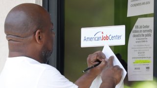 In this April 2, 2020, file photo, a resident copies down the Mississippi unemployment benefit website after being unable to enter the state WIN Job Center in north Jackson, Miss.