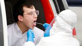 A young man is tested for COVID-19 by medical personnel wearing protective gear as part of the government's measures to help stop the spread of the coronavirus in the orthodox city of Bnei Brak, a Tel Aviv suburb, Israel, March 31, 2020.