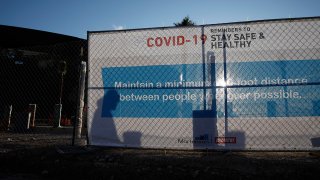 A worker casts a shadow on a sign with guidelines for protection from COVID-19 as construction continues at Allegiant Stadium, future home of the Raiders NFL football team, during the coronavirus pandemic, March 31, 2020, in Las Vegas.