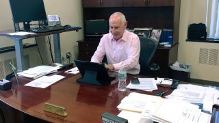 In this Monday, Dec. 30, 2019, photo, Mark Ojakian, president of the Connecticut State Colleges and Universities system, works at his office in Hartford, Conn. Ojakian is pressing ahead with a plan to consolidate the state’s 12 community colleges by 2023, despite opposition from some professors and staff. (AP Photo/Susan Haigh)