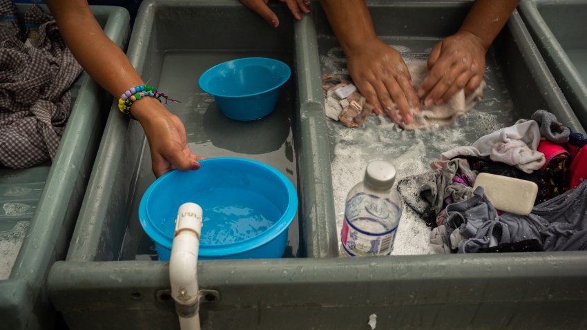 Asylum seekers wash their clothes at a makeshift migrant camp in Matamoros, Tamaulipas state, Mexico, on Friday, March 20, 2020. President Donald Trump said "non-essential" travel will be suspended across the U.S. border with Mexico as the countries combat the coronavirus outbreak.