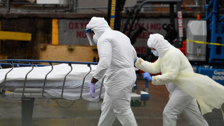 In this April 9, 2020 file photo, medical personnel move a deceased patient to a refrigerated truck serving as make shift morgues at Brooklyn Hospital Center in New York City.