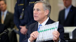 Texas Governor Greg Abbott displays COVID-19 test collection vials as he addresses the media during a press conference held at Arlington Emergency Management on March 18, 2020 in Arlington, Texas.