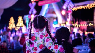 A Mother and child (7 years old) are waiting to see Santa at a Christmas tree lighting ceremony.