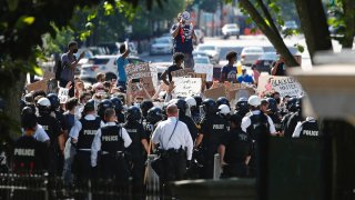 Protesters gather in front of a line of Uniformed U.S. Secret Service as demonstrators gather to protest the death of George Floyd, near the White House, Saturday, May 30, 2020, in Washington. Floyd died after being restrained by Minneapolis police officers.