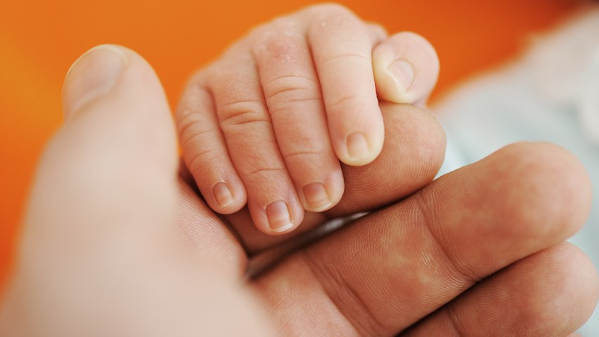 Newborn baby hand on hands