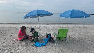 Child makes snowman oout of sand