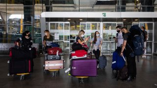 In this June 21, 2020, file photo, passengers wearing face masks arrive at Adolfo Suarez-Barajas international airport, outskirts Madrid, Spain, Sunday, June 21, 2020.