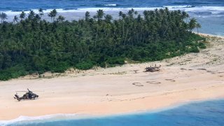 In this photo provided by the Australian Defence Force, an Australian Army helicopter lands on Pikelot Island in the Federated States of Micronesia, where three men were found, Sunday, Aug. 2, 2020, safe and healthy after missing for three days. The men were missing in the Micronesia archipelago east of the Philippines for nearly three days when their "SOS" sign was spotted by searchers on Australian and U.S. aircraft, the Australian defense department said.