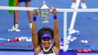 Naomi Osaka, of Japan, holds up the championship trophy after defeating Victoria Azarenka