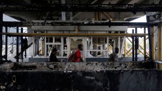 People walk through burnt toll gates with anti police slogans sprayed across, in Lagos