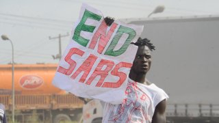 A protester holds a sign reading "End SARS"