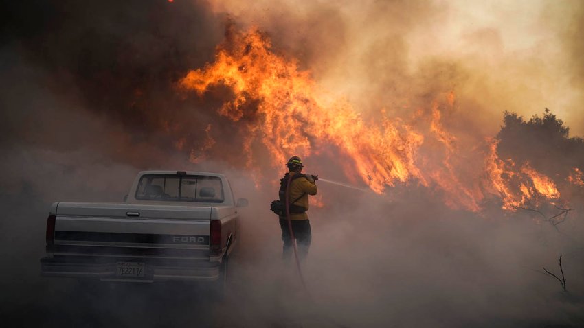 Firefighter Raymond Vasquez battles the Silverado Fire, Oct. 26, 2020, in Irvine, Calif. A fast-moving wildfire forced evacuation orders for 60,000 people in Southern California on Monday as powerful winds across the state prompted power to be cut to hundreds of thousands to prevent utility equipment from sparking new blazes.