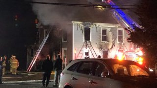 fire ladders extended over a fire-damaged house