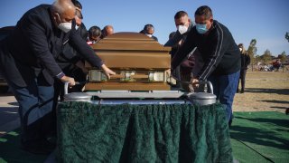 Family and friends place Humberto Rosales casket, who passed away from Covid-19 complications, at his gravesite at Memorial Pines Cemetery in Santa Teresa, New Mexico, on December 3, 2020.