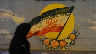 TEHRAN, IRAN - SEPTEMBER 18: An Iranian woman walks past an Iranian flag painted on a wall, as Iranians try to lead normal lives while bracing for renewed US sanctions on September 18, 2018 in Tehran, Iran. After President Donald Trump withdrew the US from the 2015 Iran nuclear deal last spring, Washington reimposed one set of sanctions in August, and will impose more on November 4, which are designed to cut-off Iran's oil revenue. So far this year the Iranian currency, the rial, has tumbled in value, prices have soared, and shortages of some goods like diapers/nappies have appeared.