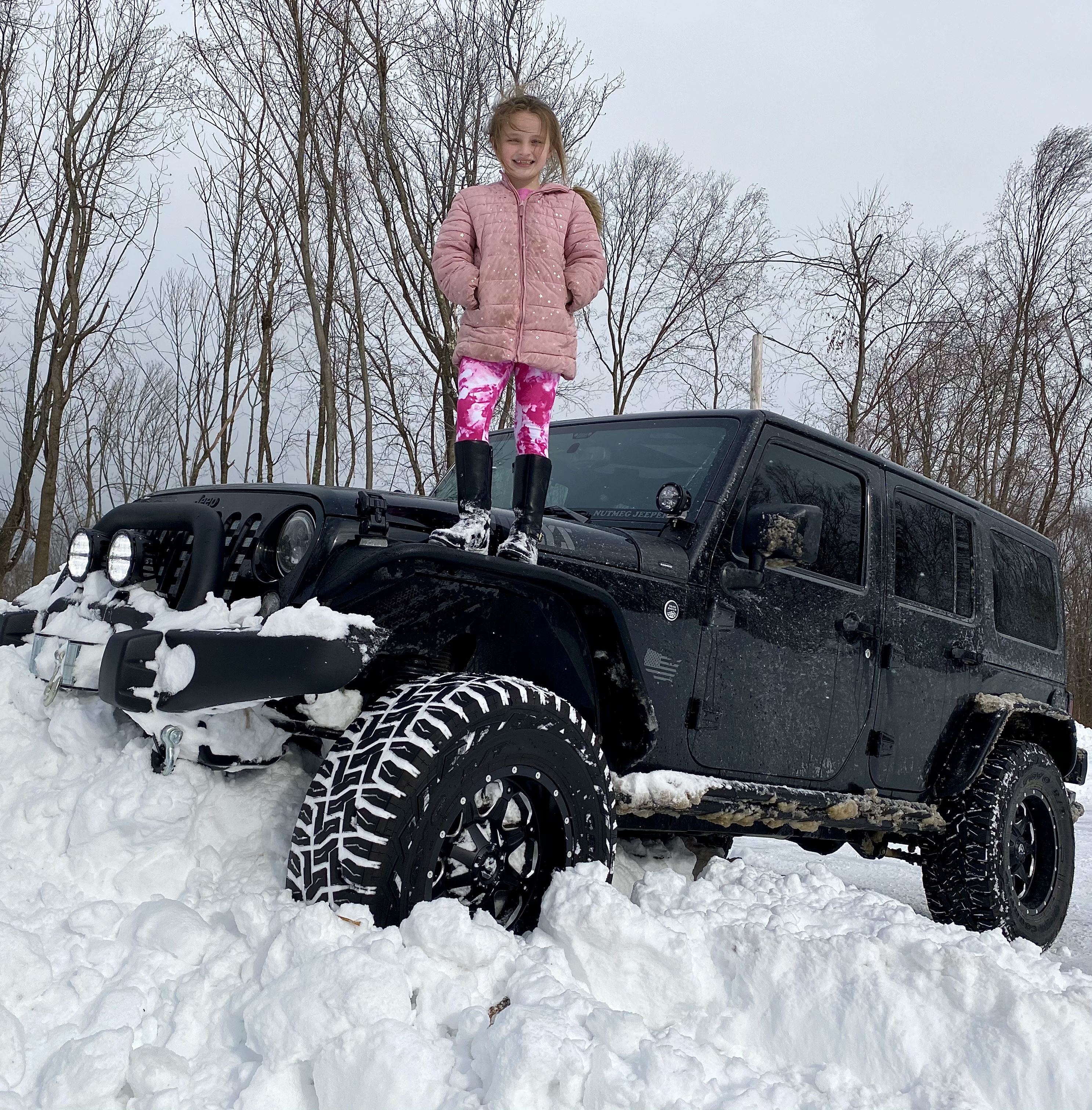 Min datter Rikey står på min jeep i en snedrive