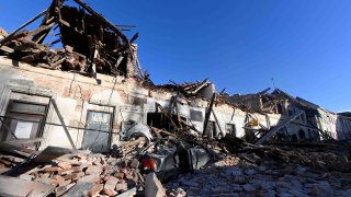 This photograph taken on December 29, 2020, shows the wreckage of a car and damaged buildings in Petrinja, some 50kms from Zagreb, after the town was hit by an earthquake of the magnitude of 6.4.