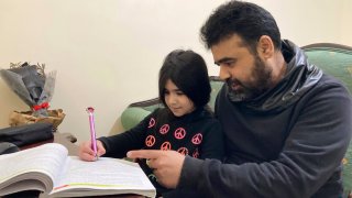 Syrian refugee Mahmoud Mansour, 47, helps his youngest daughter Sahar, 8, with her homework at his rented apartment in Amman, Jordan, Wednesday, Jan. 20, 2021. President Joe Biden has vowed to restore America's place as a world leader in offering sanctuary to the oppressed by raising the cap on the number of refugees allowed in each year. Mansour's family had completed the work to go to the United States when the Trump administration issued its travel ban barring people from Syria indefinitely and suspending the refugee program for 120 days.