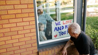 Grandfather visiting family with granddaughter (2-3) through window