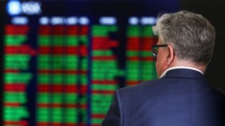 A man looks at an electronic board displaying stock information at the Australian Securities Exchange in Sydney, Australia, on Tuesday, Feb. 6, 2018.