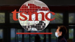 A man walks past TSMC’s logo at the company’s headquarters in Hsinchu, Taiwan. TSMC is the world’s largest semiconductor foundry.