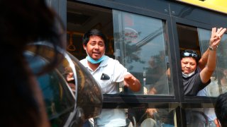 An arrested protester flashes the three-fingered salute while onboard a bus getting out of Insein prison to go to an undisclosed location Wednesday, March 24, 2021 in Yangon, Myanmar.