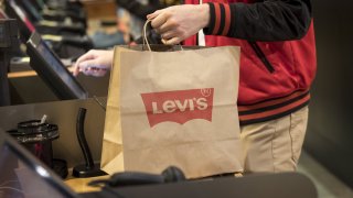 An employee holds a shopping bag while ringing up a customer at the Levi Strauss & Co. flagship store in San Francisco, March 18, 2019.