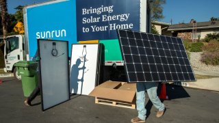 Aaron Newsom, left, an installer for the solar company, Sunrun, and Tim McKibben, a senior installer, prepare solar panels to be installed on the roof of a home in Granada Hills.
