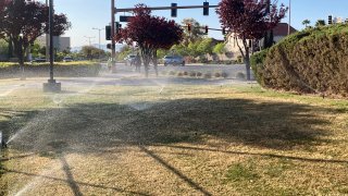 Sprinklers water grass near a street corner in Las Vegas