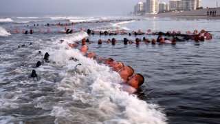 FILE – This May 4, 2020, photo provided by the U.S. Navy shows SEAL candidates participating in “surf immersion” during Basic Underwater Demolition/SEAL (BUD/S) training at the Naval Special Warfare (NSW) Center in Coronado, Calif.