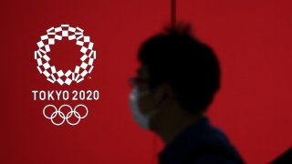 A pedestrian walks past a Tokyo 2020 Olympic Games logo on a decoration board in Tokyo on April 7, 2021.