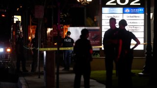 Police officers stand outside a business building where a shooting occurred in Orange, Calif., Wednesday, March 31, 2021. Police say several people were killed, including a child, and the suspected shooter was wounded by police.