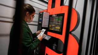 A woman uses a Bitcoin ATM machine placed within a safety cage on January 29, 2021 in Barcelona, Spain.
