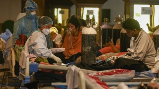 Health workers wearing personal protective equipment attend to Covid-19 patients inside a banquet hall temporarily converted into a Covid care center in New Delhi on May 7, 2021.
